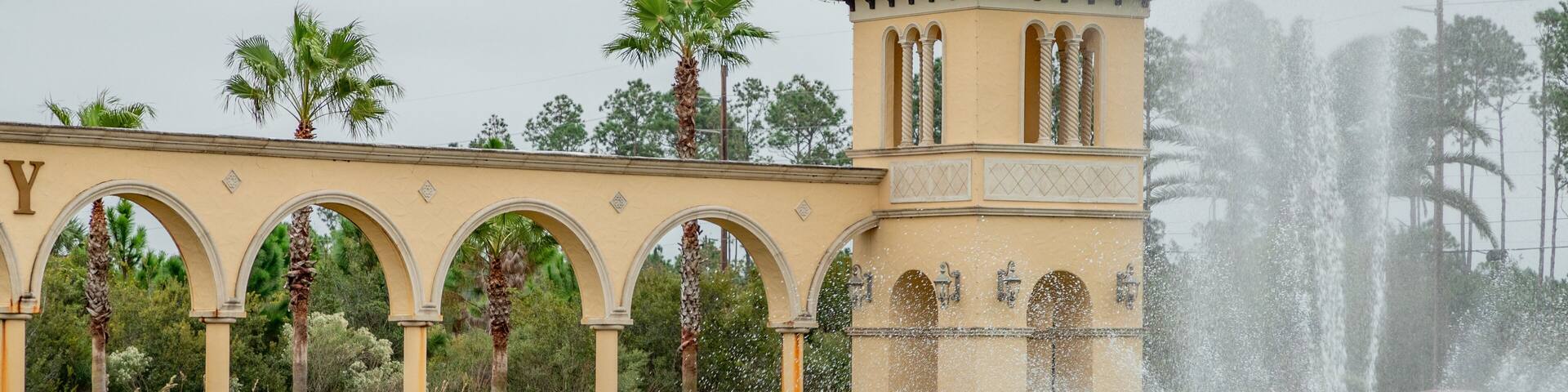 Una fuente, palmeras y un edificio con arcos.