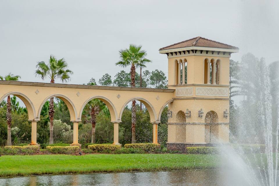 Une fontaine, des palmiers et un bâtiment orné d’arches.