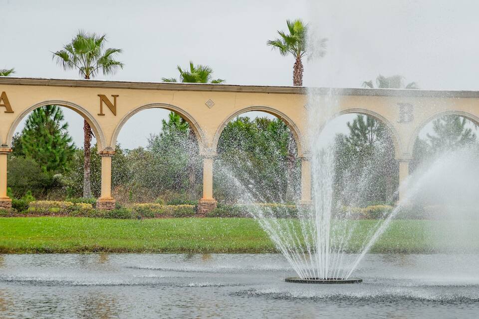 Una fuente con chorros de agua en un parque, con un edificio al fondo.