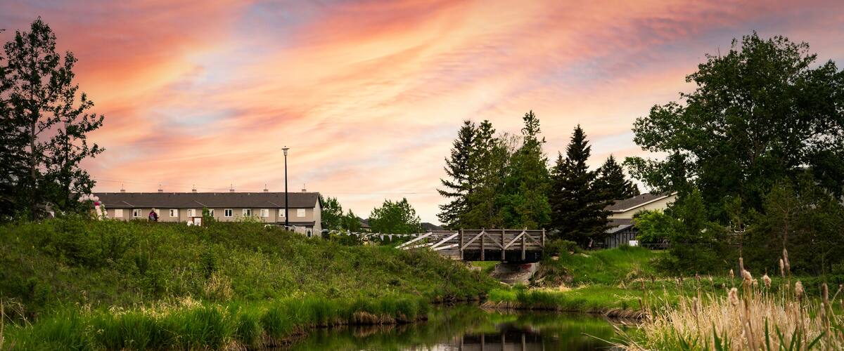 Small creek in a community recreation area with a sunset reflecting on the water at Nose Creek Park Airdrie Alberta Canada.
