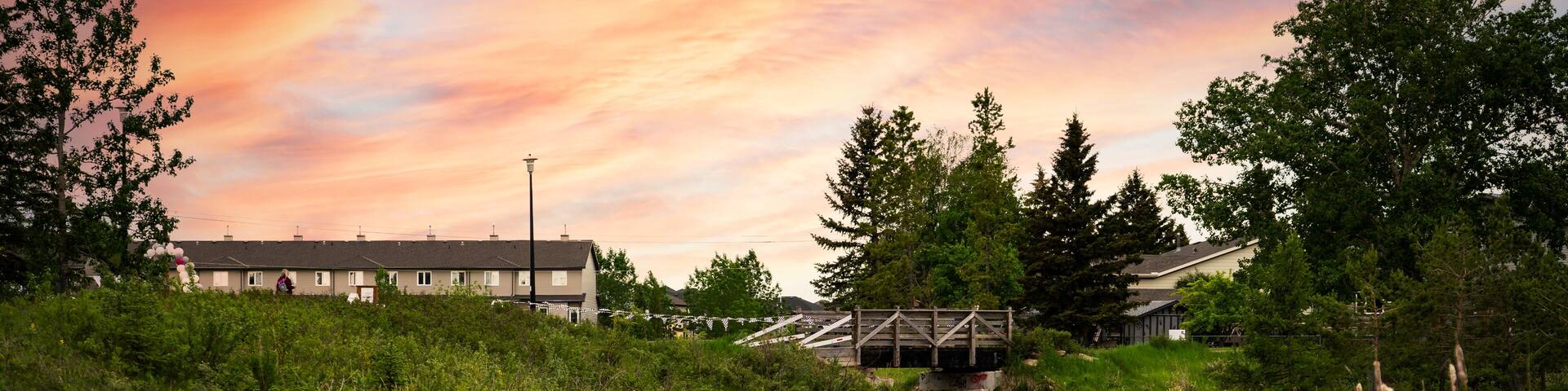 Small creek in a community recreation area with a sunset reflecting on the water at Nose Creek Park Airdrie Alberta Canada.