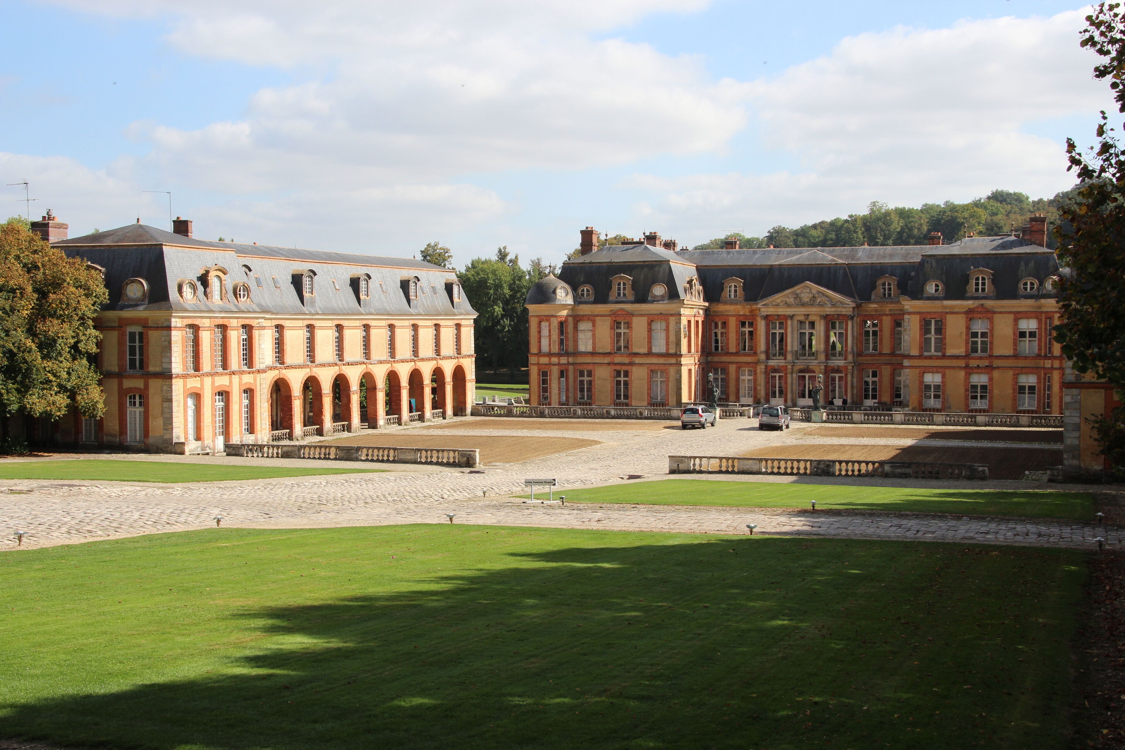 A large, historic building complex with a courtyard and lush green lawns.