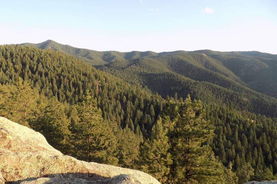 Un paysage montagneux caractérisé par de vastes forêts et des affleurements rocheux.