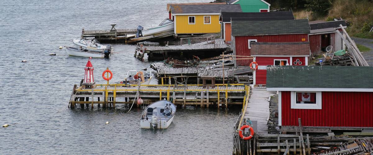 A coastal village with colorful houses, a dock with boats, and a lighthouse.