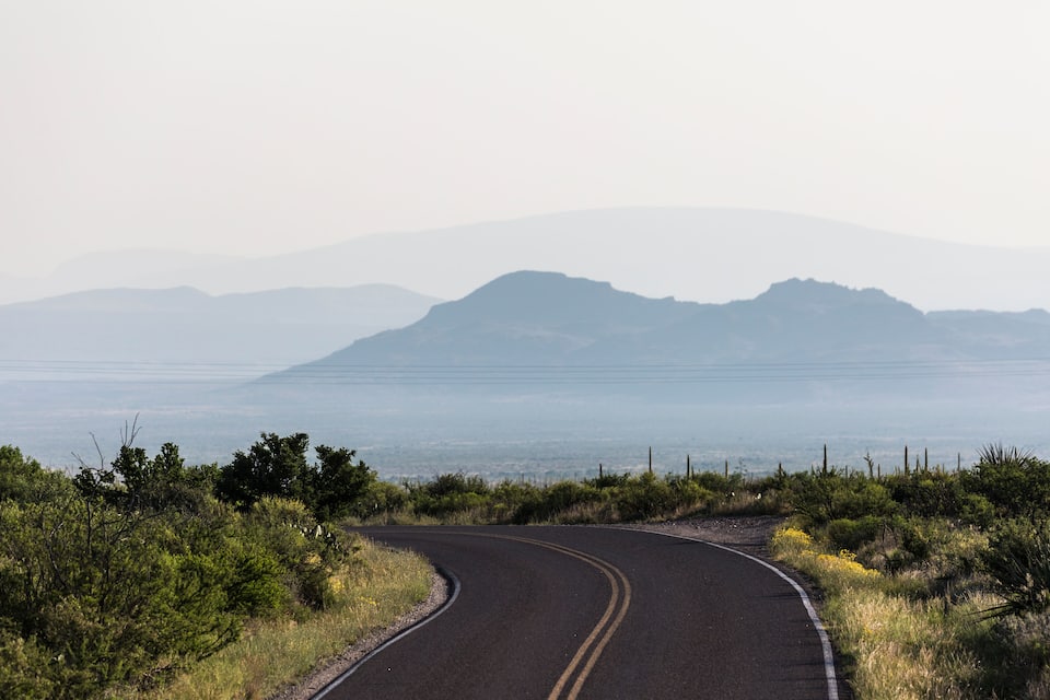 Un camino sinuoso con una cordillera en el fondo.