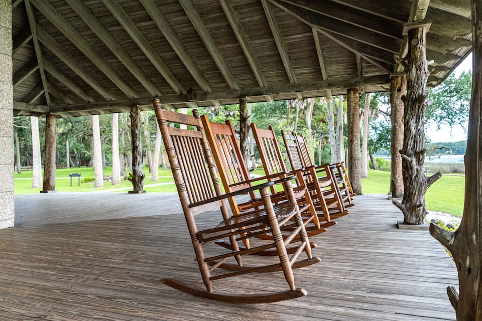 A wooden deck with rocking chairs and a covered area with a wooden ceiling.