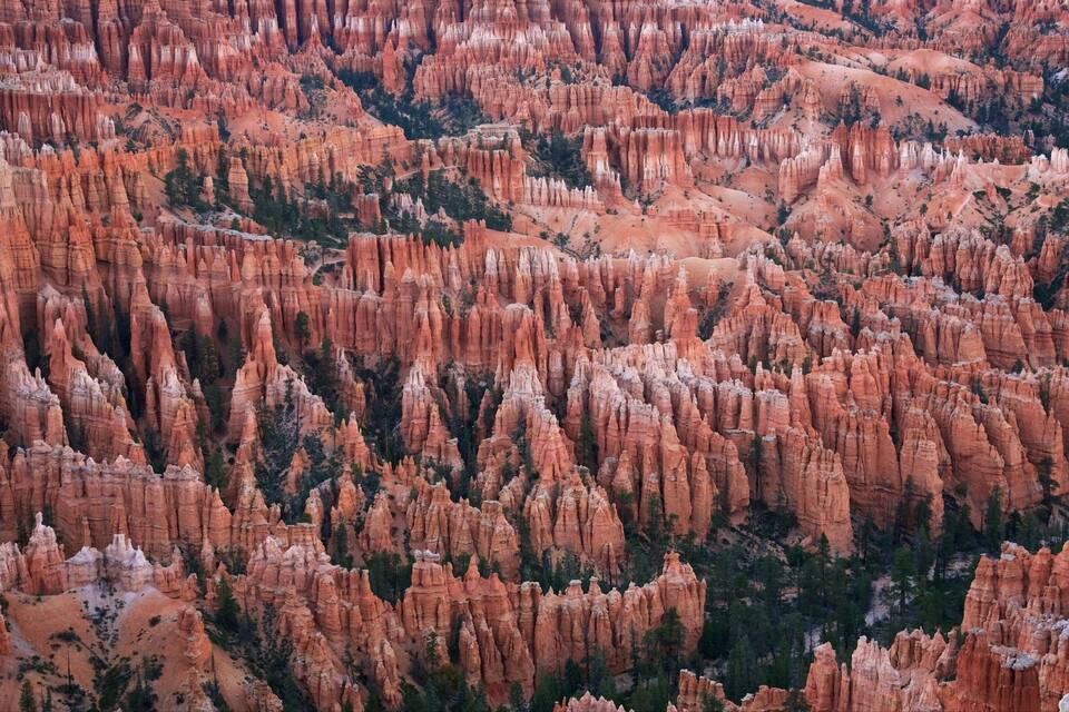 A vast array of red rock formations with sharp peaks and deep canyons.