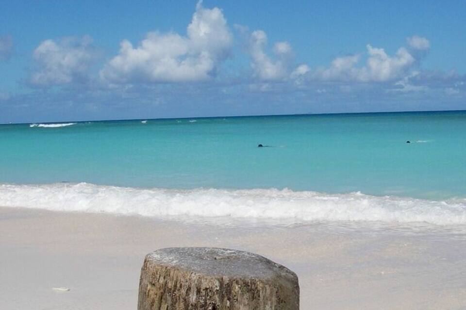 Platja sorrenca amb una roca gran al primer pla i aigües turqueses tranquil·les.