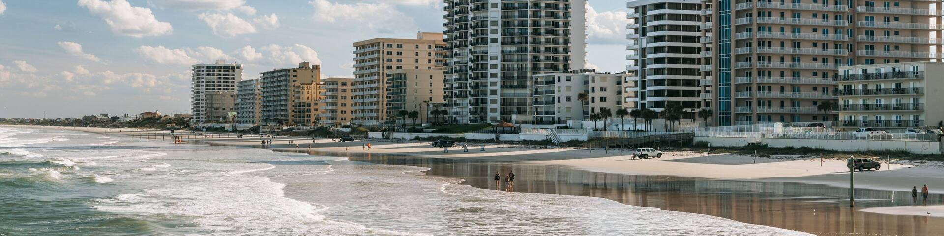 A beach with waves, a sandy shore, and several high-rise buildings in the background.