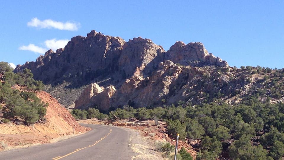 A winding road with rocky mountains in the background.