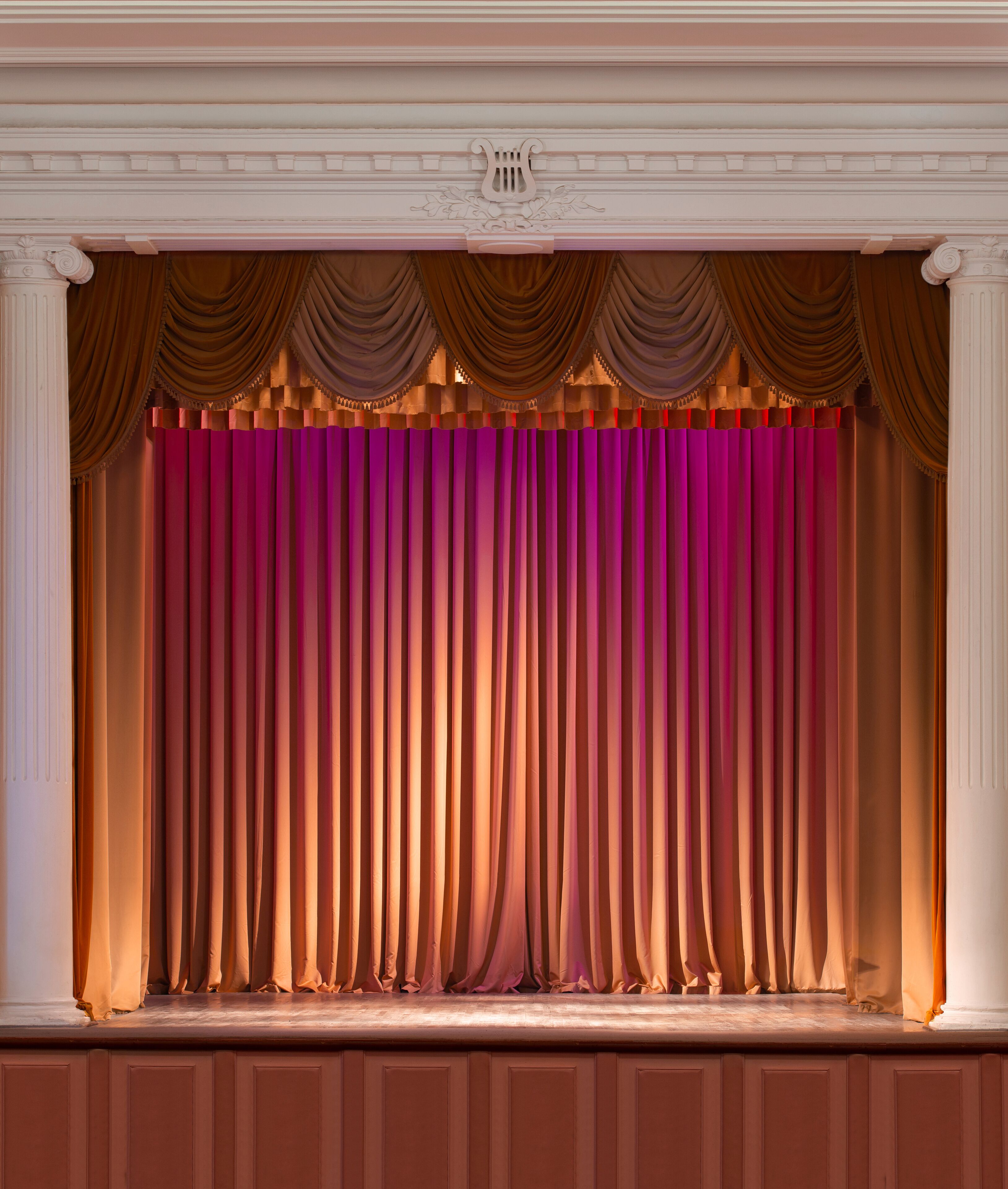 illuminated by lights stage with backstage and decorative columns, there is an old grand piano