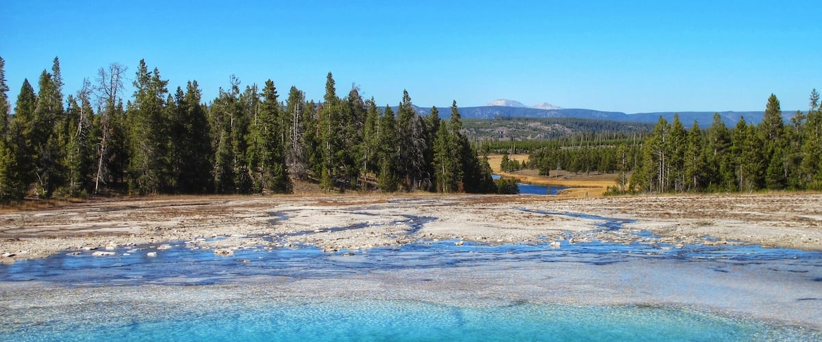 Opal Pool with a glimpse of Firehole River through the tree and Mount Holmes beyond in the distance #nationalpark #blue #nature