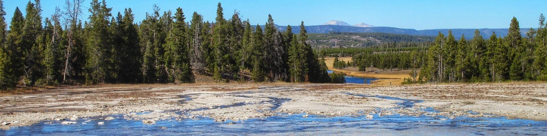 Opal Pool with a glimpse of Firehole River through the tree and Mount Holmes beyond in the distance #nationalpark #blue #nature