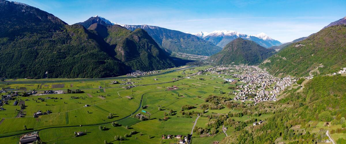 A valley with a town surrounded by mountains and fields.