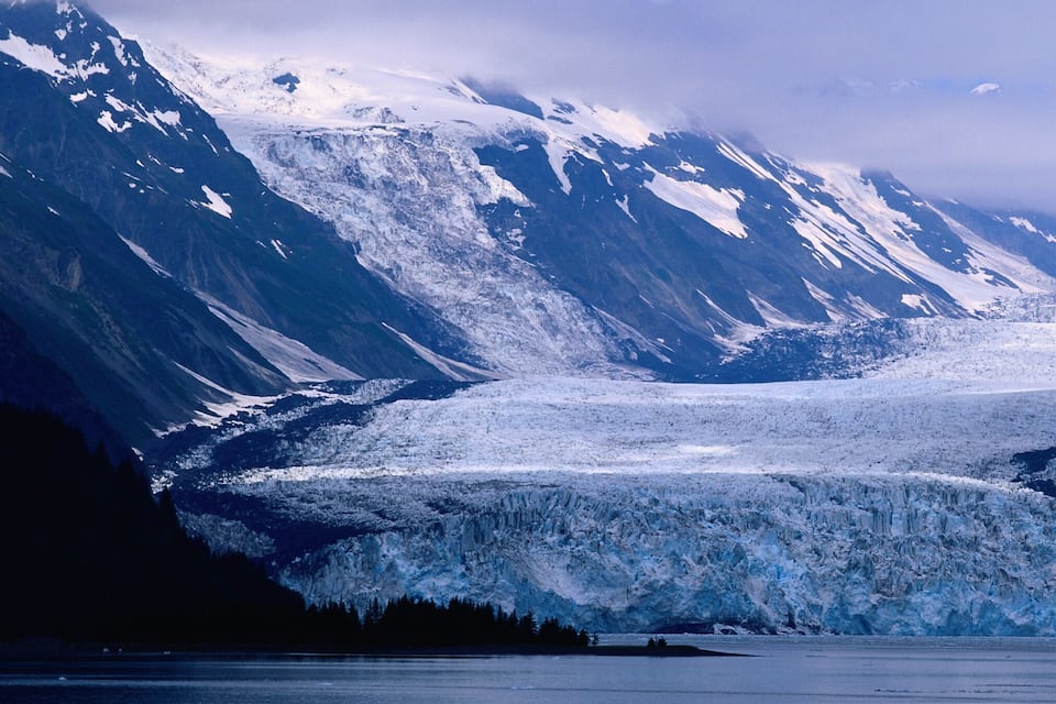 A glacier with steep, snow-covered mountains in the background.