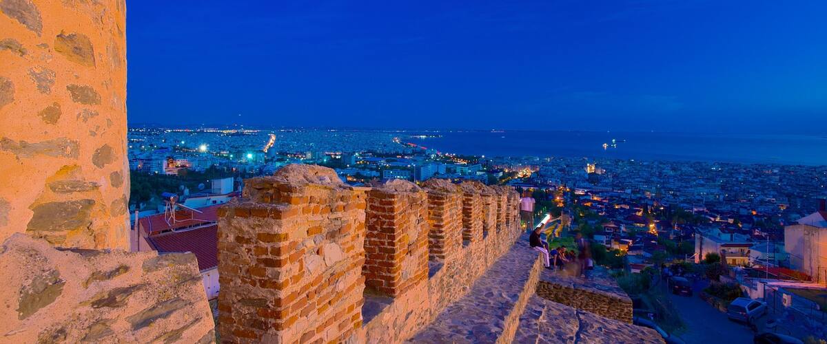 A historic stone wall overlooking a cityscape at dusk.