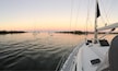 A calm body of water with several sailboats at sunset.