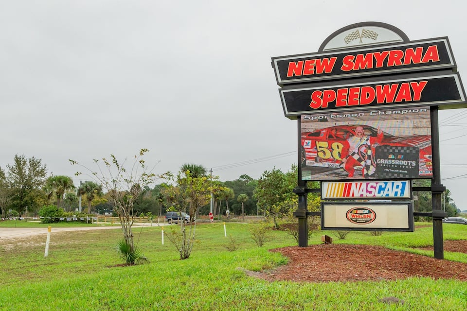A New Smyrna Speedway sign with a NASCAR All-American Whelan Brothers banner.