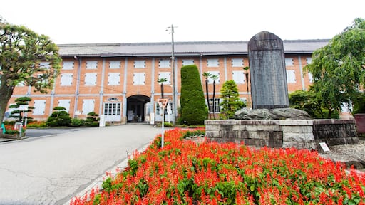 A red brick building with a large stone monument in front.