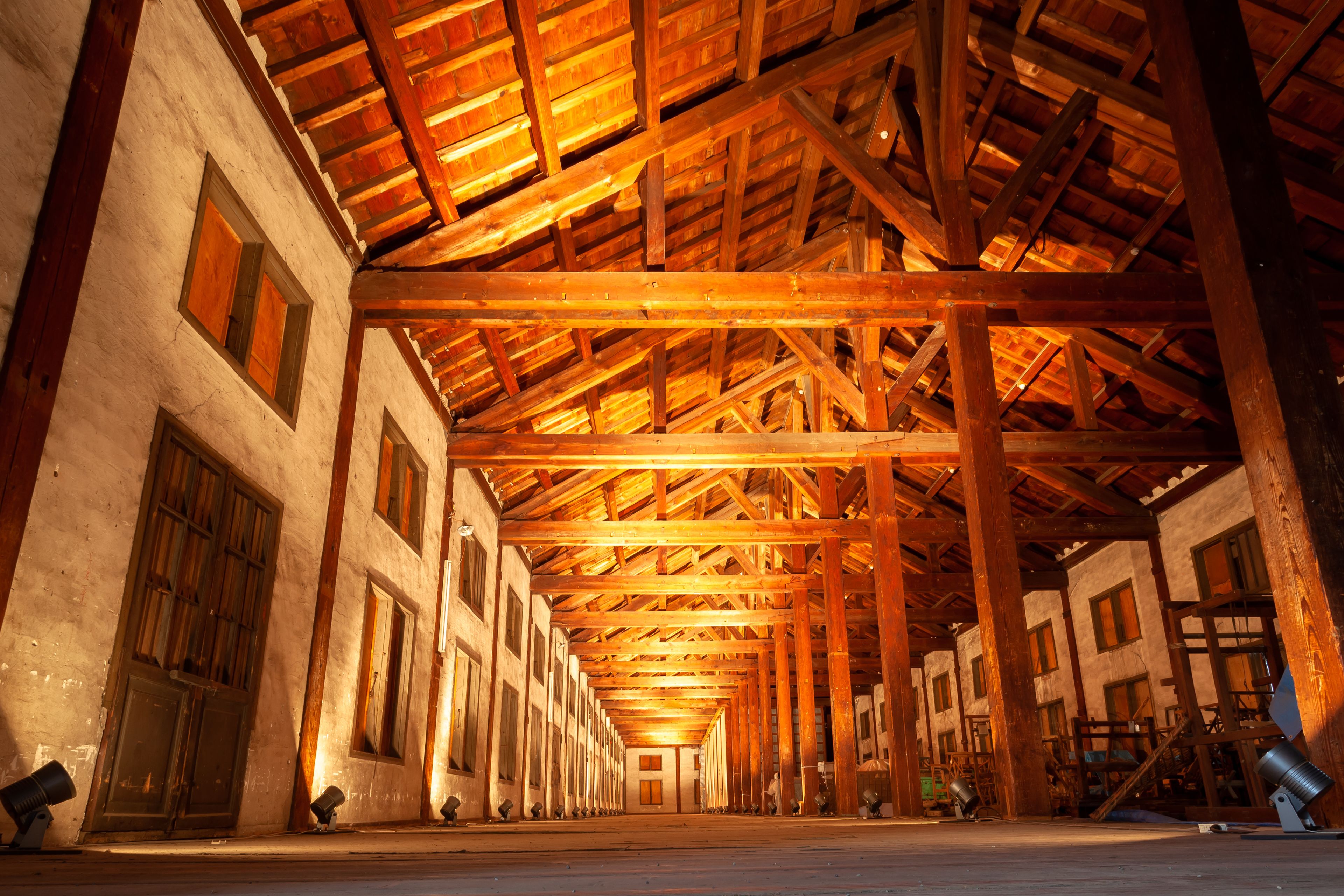 A large industrial building with a high wooden ceiling and multiple windows.