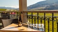 A bottle of Burrowing Owl Chardonnay and a glass on a table with a view of a mountainous landscape.