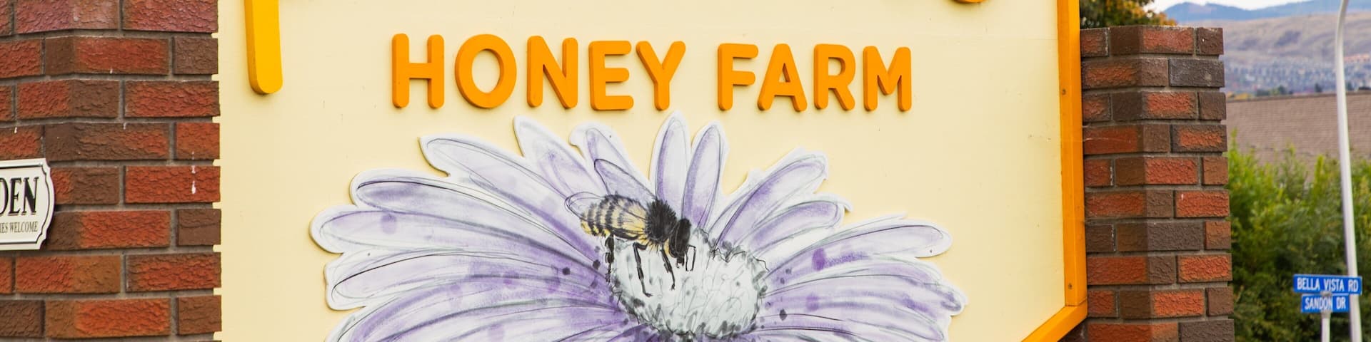 A sign for Planet Bee Honey Farm with a bee illustration.