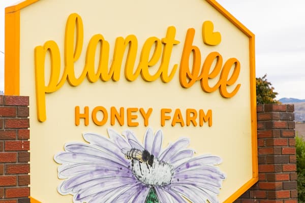 A sign for Planet Bee Honey Farm with a bee illustration.