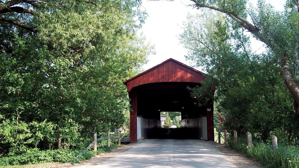 A covered bridge surrounded by lush greenery.