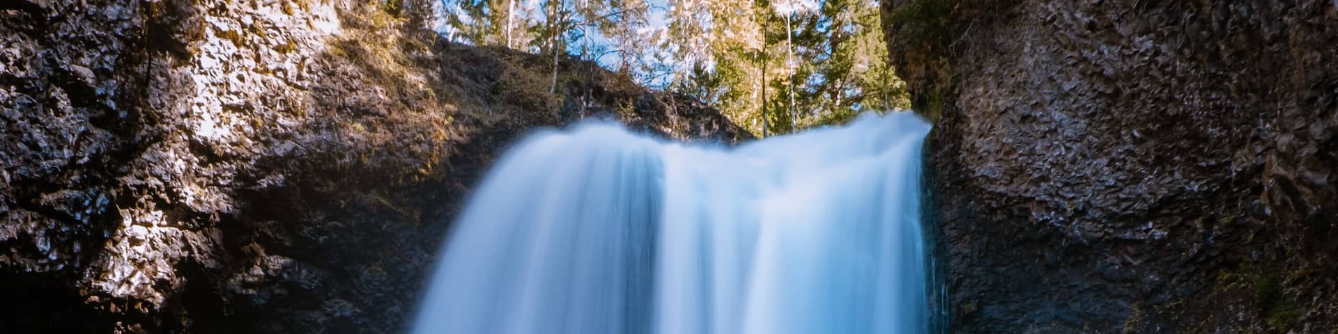 A waterfall cascading down a rocky cliff surrounded by trees.