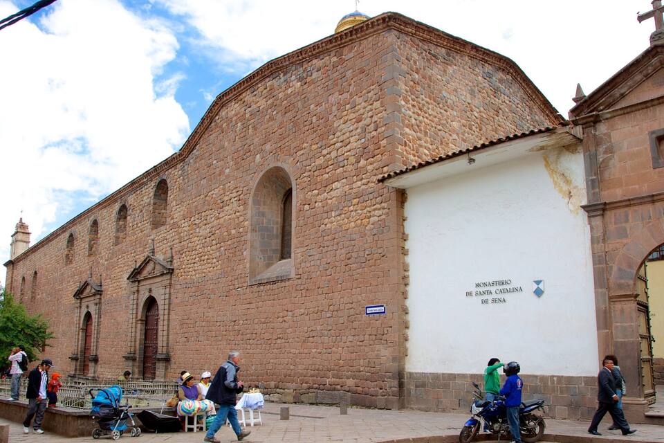 A historic church with a large white wall and a sign reading "Monasterio de Santa Catalina de Sena".