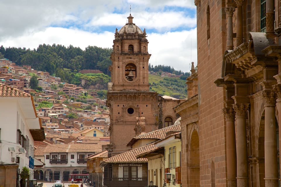 A historic town with a prominent bell tower, terracotta-roofed buildings, and a hillside backdrop.