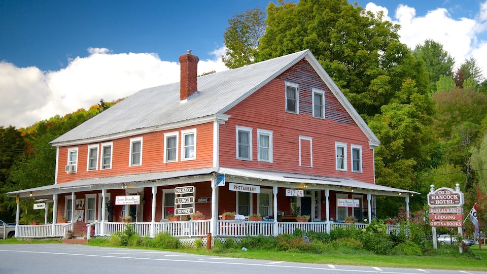 A red building with a white porch and multiple signs advertising breakfast, lunch, dinner, and lodging.