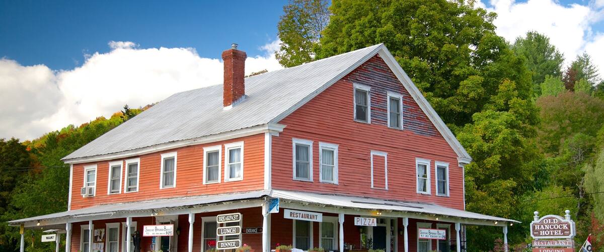 A red building with a white porch and multiple signs advertising breakfast, lunch, dinner, and lodging.