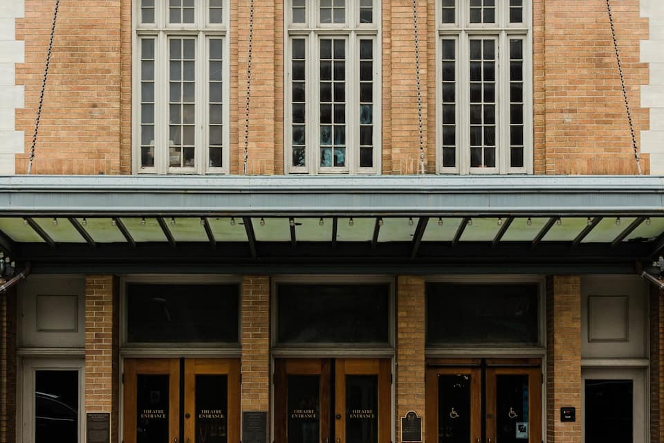 Un edificio de ladrillo con ventanas de arco y un acceso cubierto.