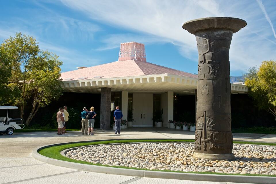 A building with a distinctive red roof and a large stone column with carvings.