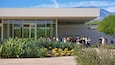 A modern building with a glass facade and a group of people gathered in front.