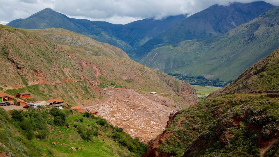 A mountainous landscape with terraced fields and a small settlement with buildings and vehicles.