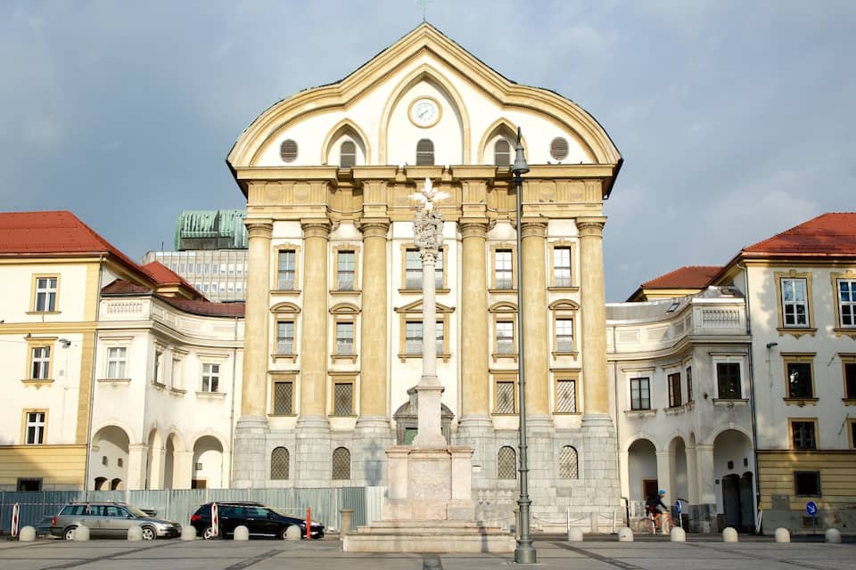 A large, ornate building with a clock tower, surrounded by other classical architecture.