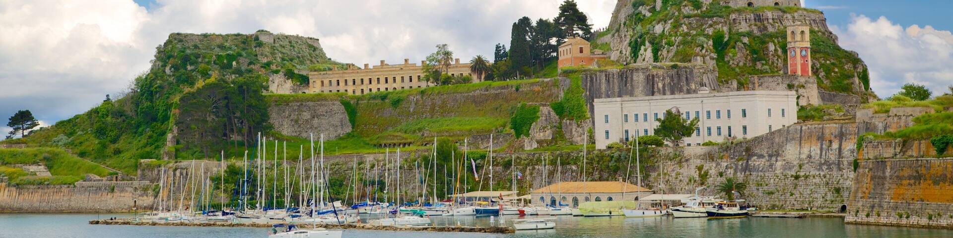 A coastal town with a prominent castle on a hill, a marina with boats, and a clear blue sky.