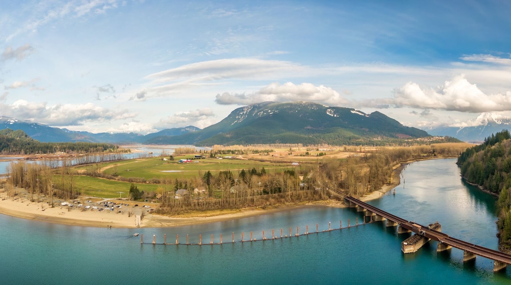 Aerial Panoramic View of a River in the valley surrounded by Canadian Mountain Landscape. Green Farms. Taken in Harrison Mills, Fraser Valley, East of Vancouver, BC, Canada.