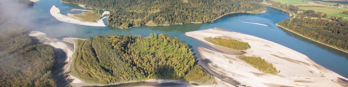 A river winding through a forested valley with mountains in the background.