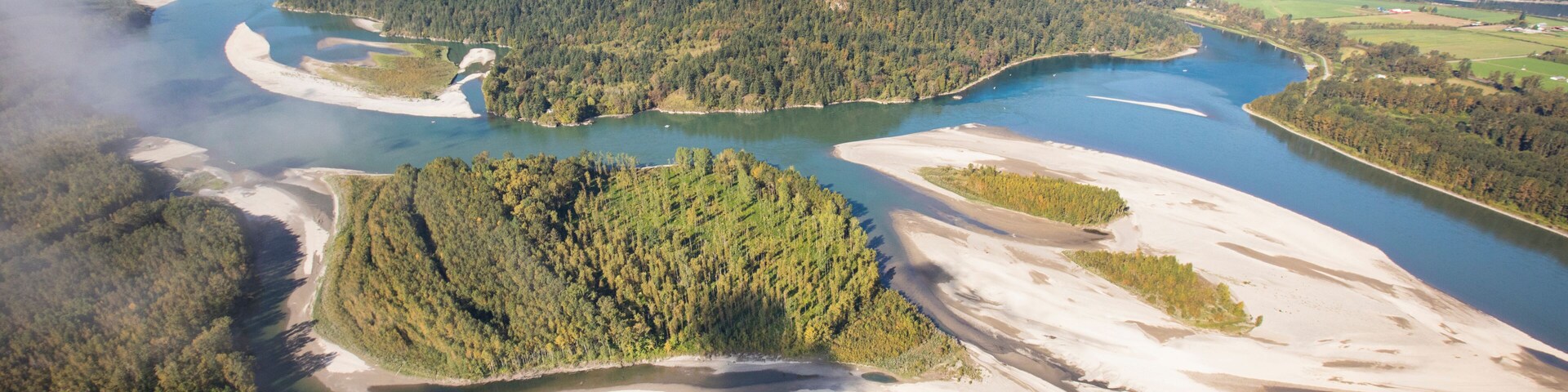 A river winding through a forested valley with mountains in the background.