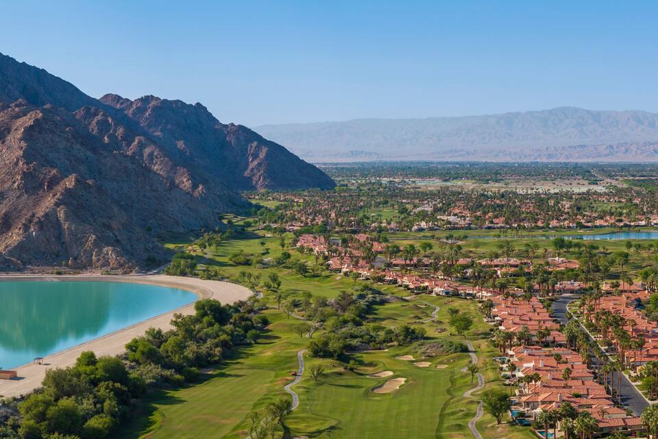 A coastal town with a mountain range, a beach, and a golf course.