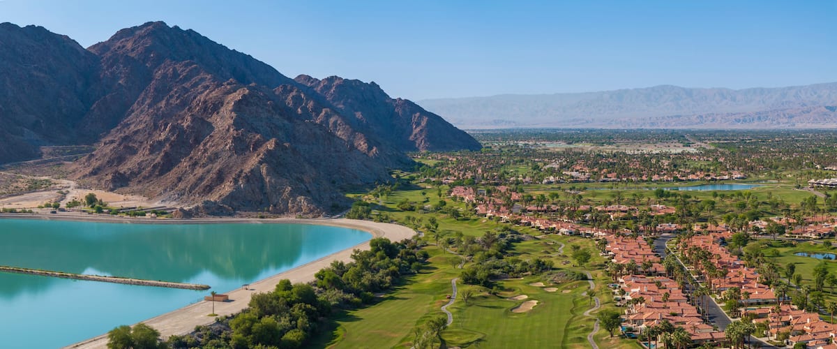 A coastal town with a mountain range, a beach, and a golf course.