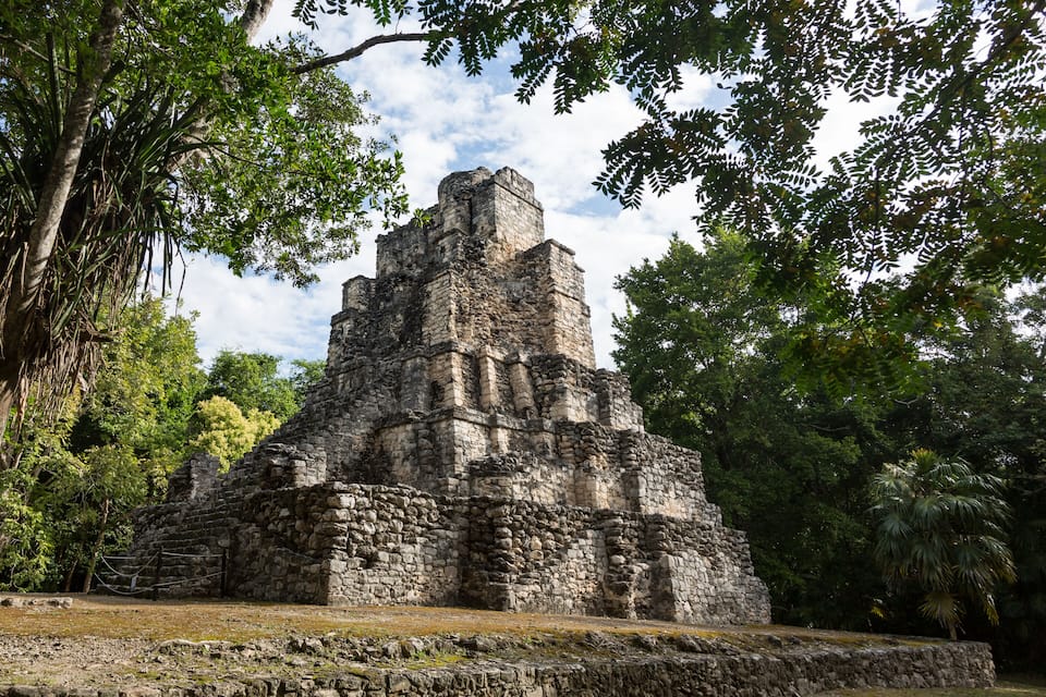 Una antigua pirámide de piedra rodeada de exuberante vegetación.