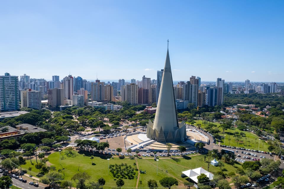 Paisagem urbana com uma torre de igreja imponente, cercada por edifícios e áreas verdes.