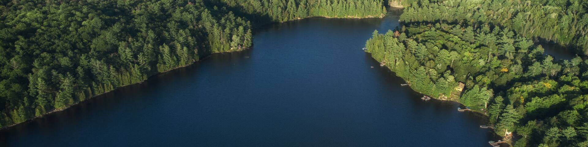 Buckskin Lake on a late summer afternoon. Aerial above the expansive crown land evergreen wilderness in Tory Hill, Highlands East, Ontario, Canada.