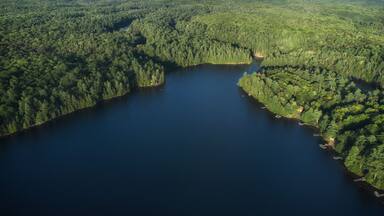 Buckskin Lake on a late summer afternoon. Aerial above the expansive crown land evergreen wilderness in Tory Hill, Highlands East, Ontario, Canada.