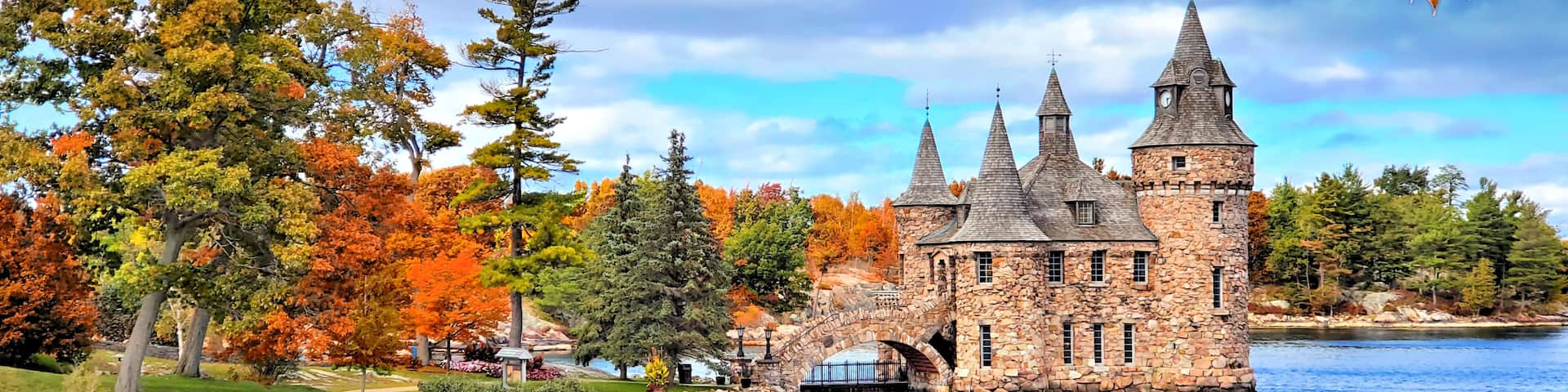 A stone castle by a lake with autumn foliage.