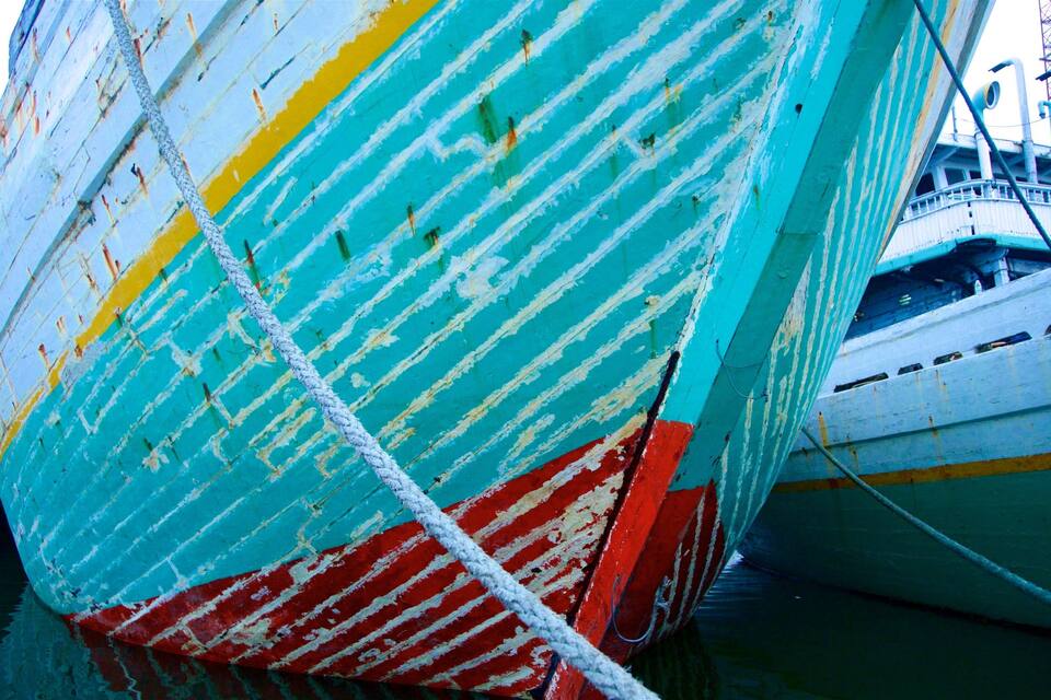 Un barco grande y colorido, con signos de desgaste y oxidación.